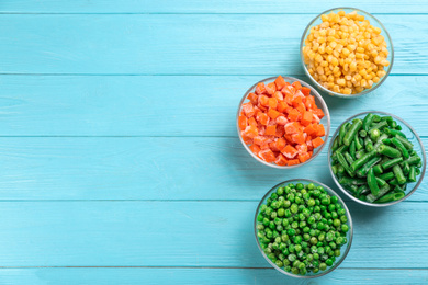 Photo of Different frozen vegetables on light blue wooden table, flat lay. Space for text