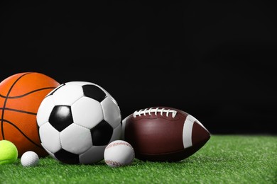 Many different sports balls on green grass against black background, space for text