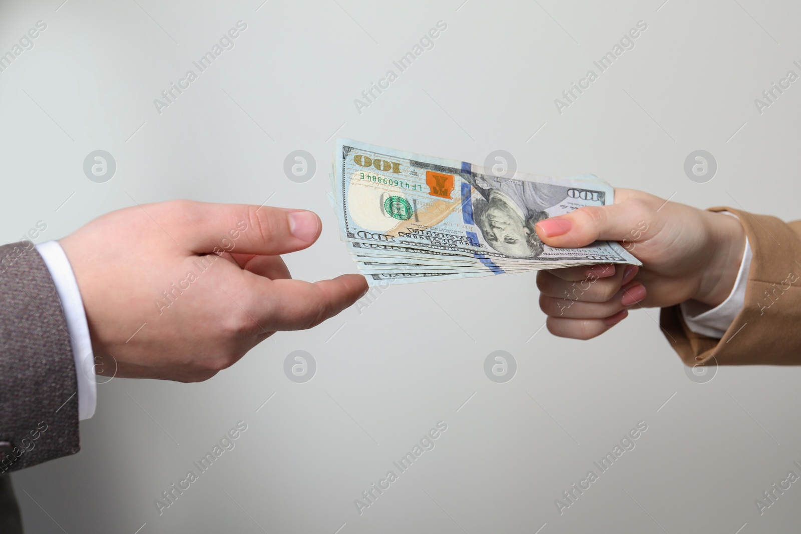 Photo of Woman giving money to man on light grey background, closeup. Currency exchange