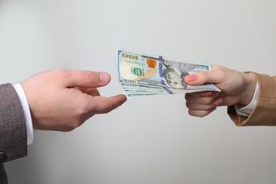 Photo of Woman giving money to man on light grey background, closeup. Currency exchange