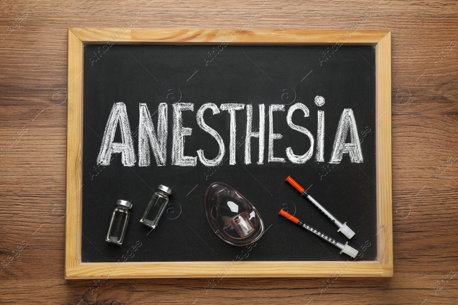 Photo of Blackboard with word Anesthesia, vials, mask and syringes on wooden table, top view