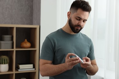 Photo of Diabetes test. Man checking blood sugar level with lancet pen at home