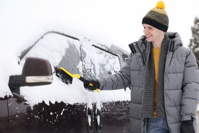 Photo of Man cleaning snow from car window outdoors