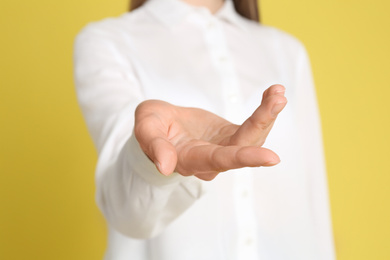 Photo of Young woman against yellow background, focus on hand
