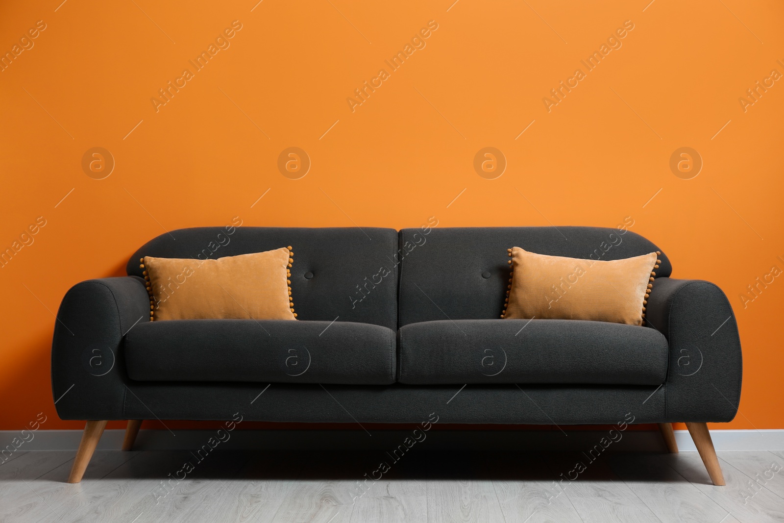 Photo of Stylish room with cosy sofa near orange wall. Interior design