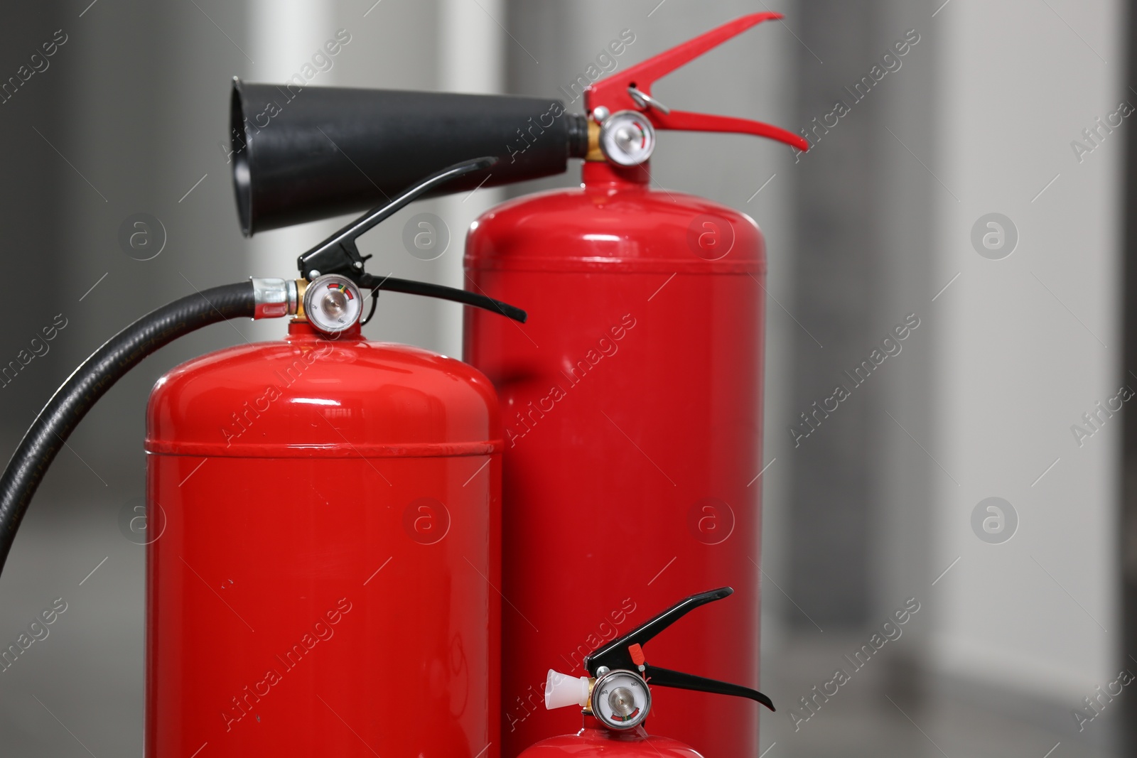 Photo of Three red fire extinguishers in hall, closeup