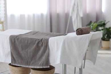 Photo of Comfortable massage table with clean towels in spa center