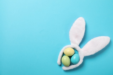 Funny headband with Easter bunny ears and dyed eggs on color background, flat lay. Space for text