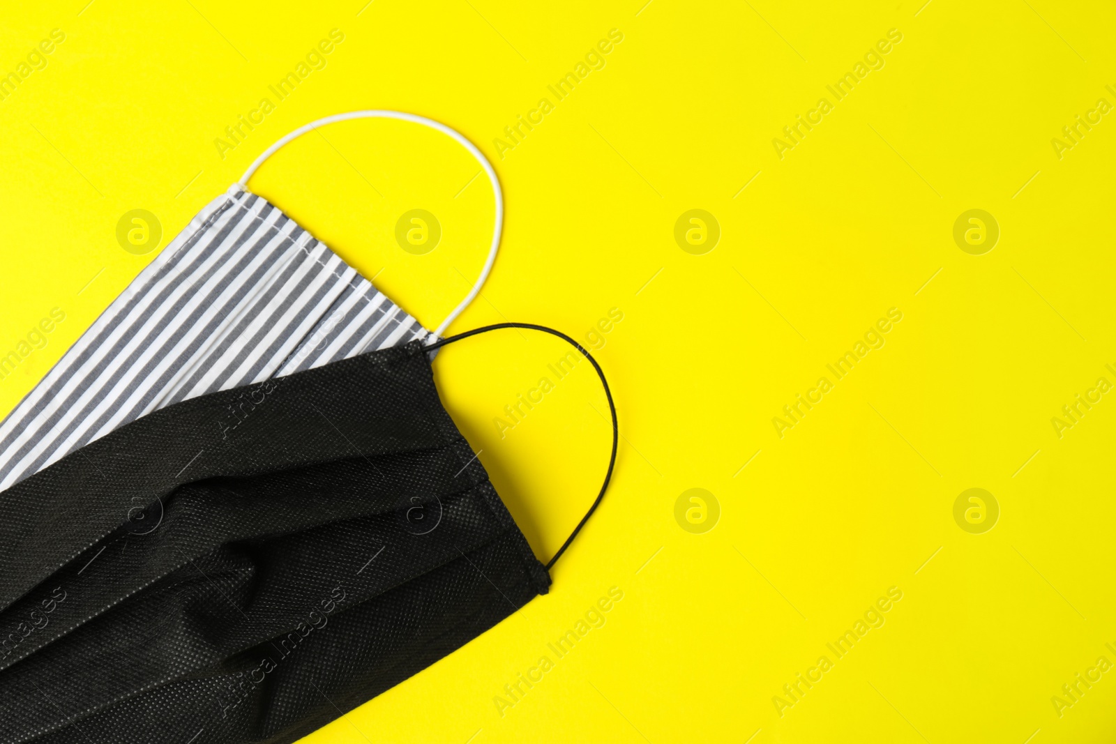 Photo of Homemade protective face masks on yellow background, flat lay. Space for text