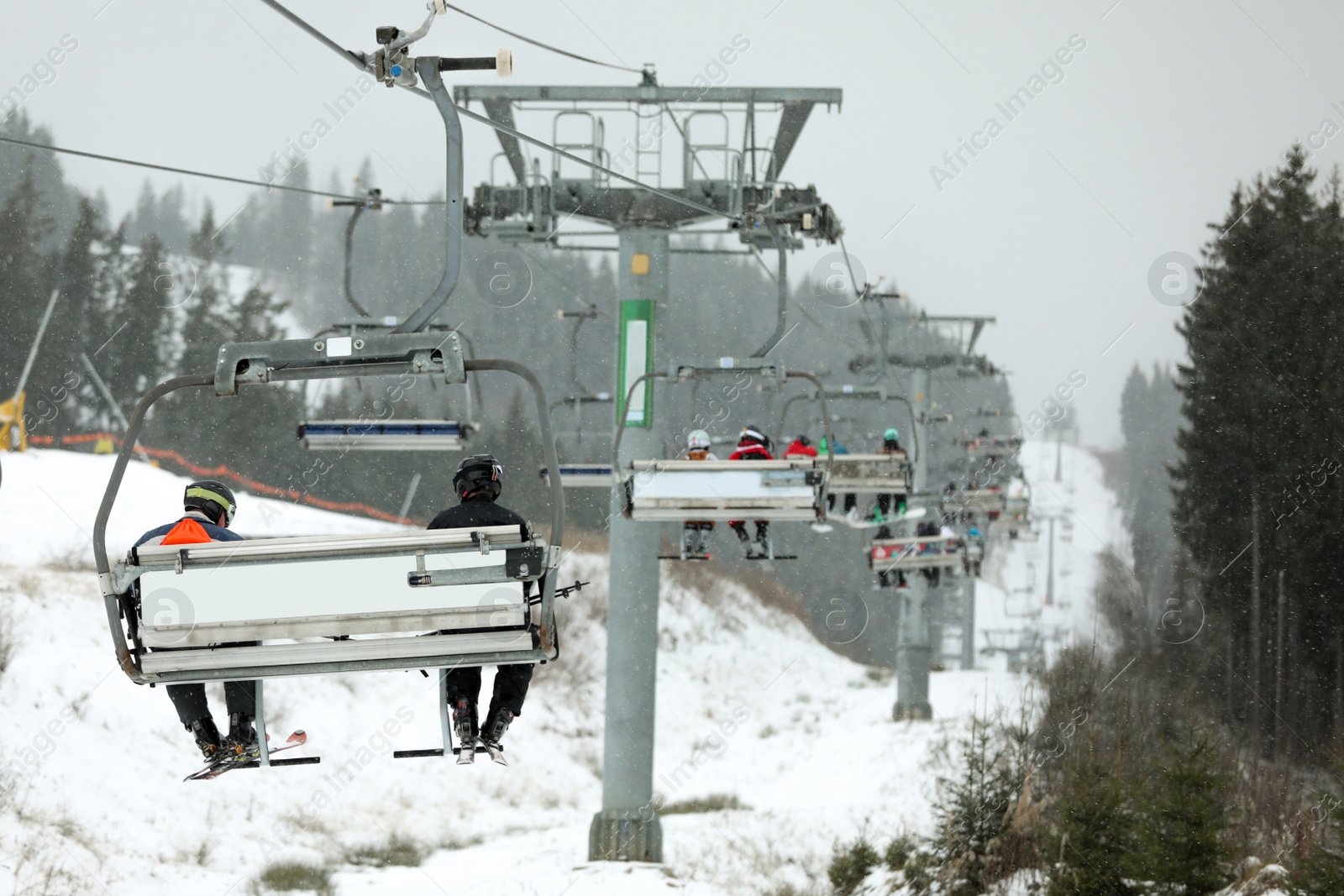 Photo of Chairlift with people at ski resort. Winter vacation