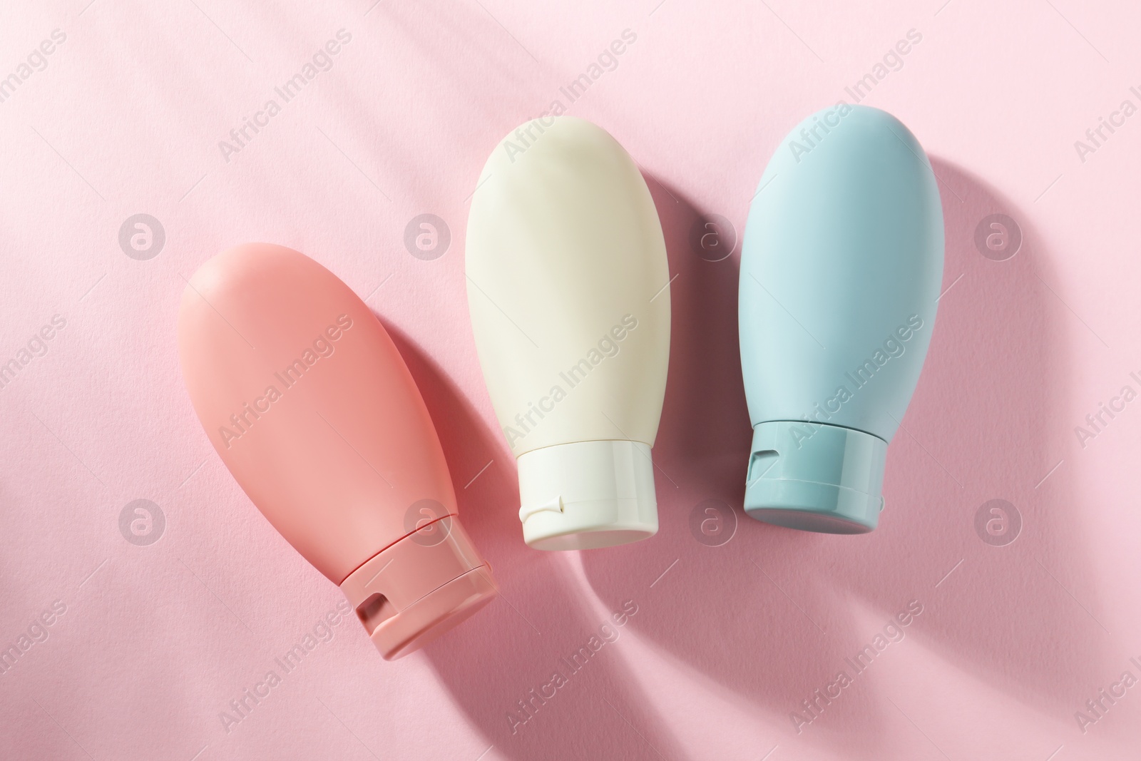 Photo of Cosmetic travel kit on pink background, top view