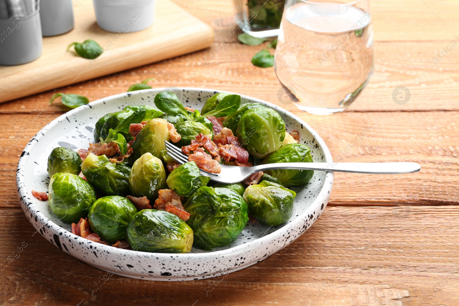 Photo of Tasty roasted Brussels sprouts with bacon on wooden table