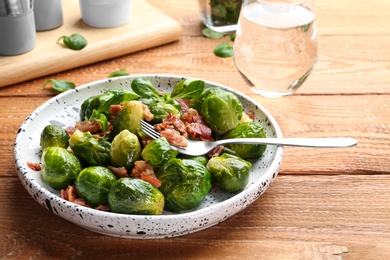 Tasty roasted Brussels sprouts with bacon on wooden table