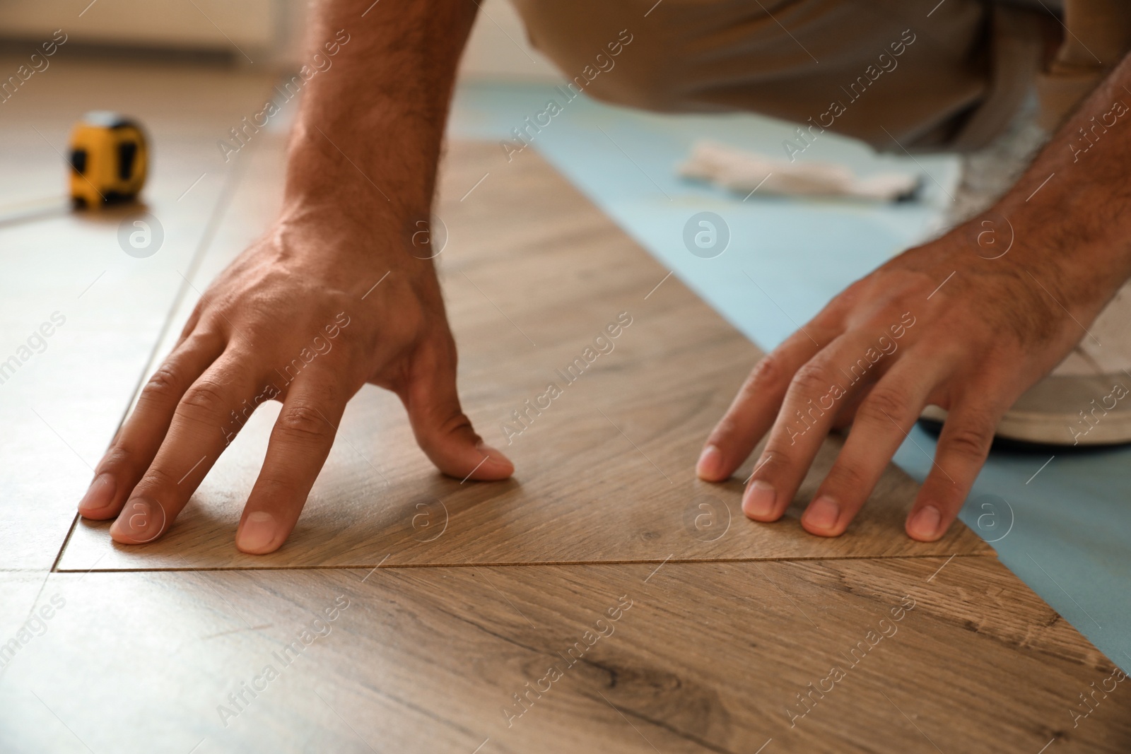 Photo of Professional worker installing new parquet flooring indoors, closeup