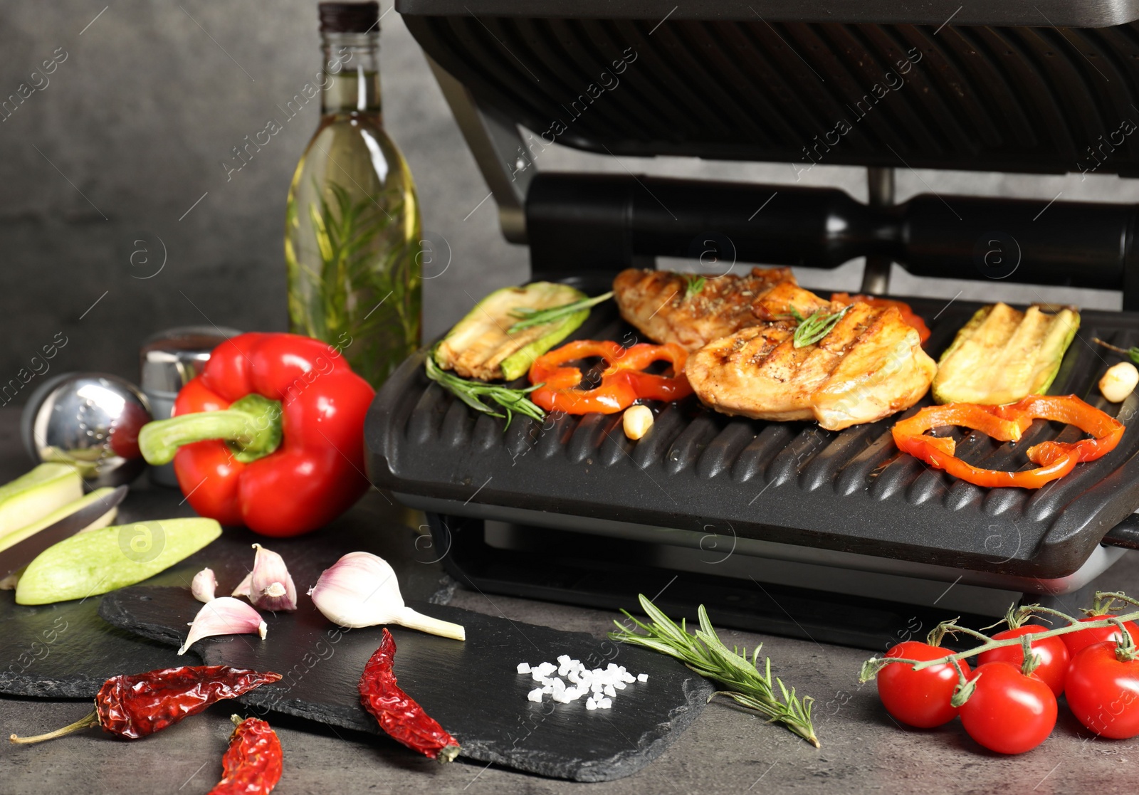 Photo of Electric grill with different products on grey textured table