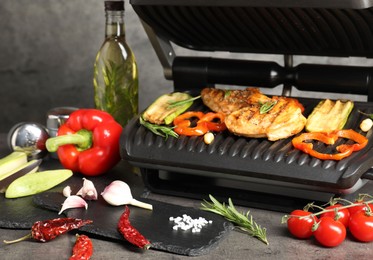 Photo of Electric grill with different products on grey textured table