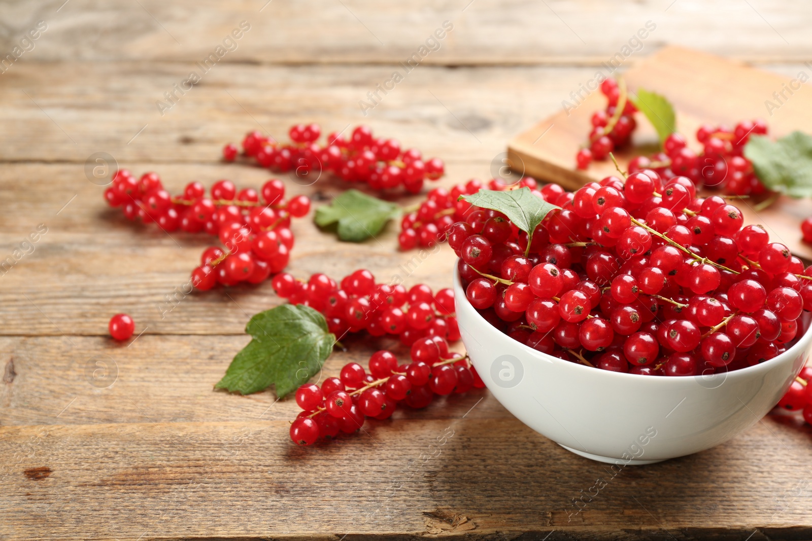 Photo of Delicious red currants on wooden table. Space for text