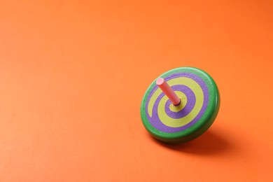 One colorful spinning top on orange background, space for text