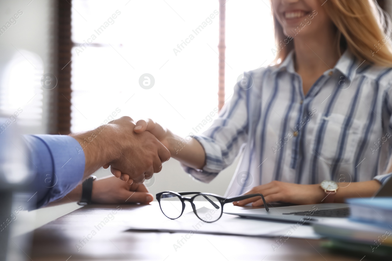 Photo of Business partners shaking hands at table after meeting in office, closeup