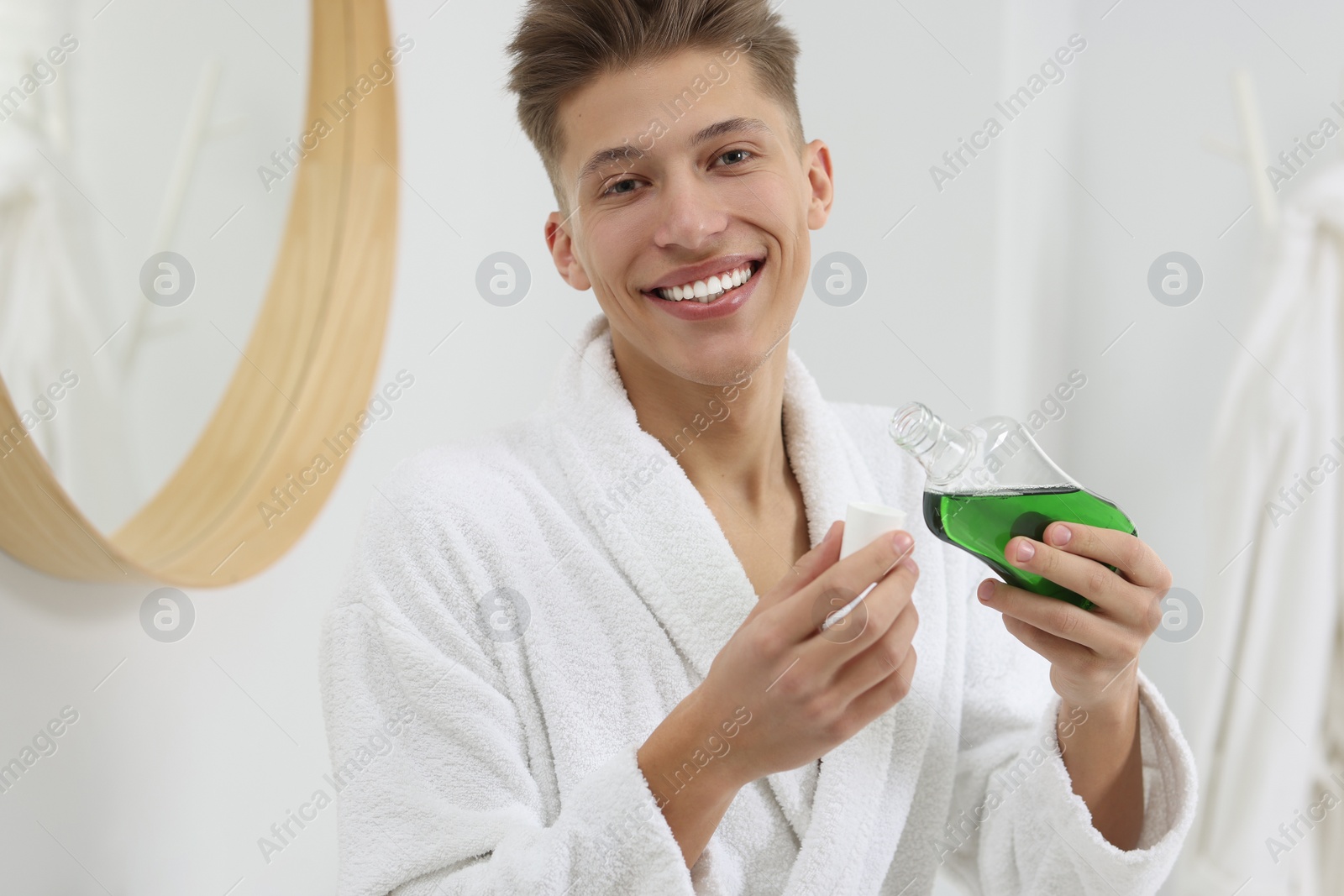 Photo of Young man with mouthwash in bathroom. Oral hygiene