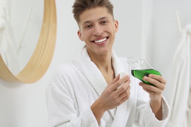 Photo of Young man with mouthwash in bathroom. Oral hygiene