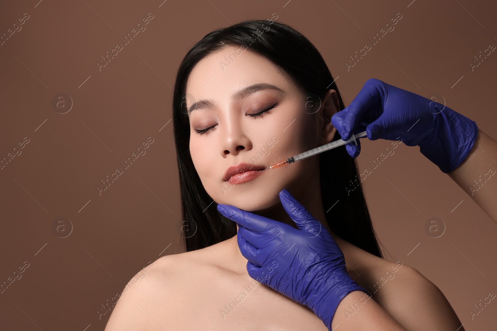 Photo of Woman getting lip injection on brown background