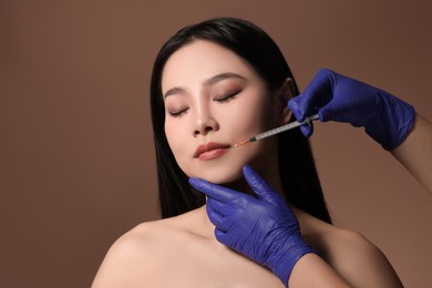 Woman getting lip injection on brown background