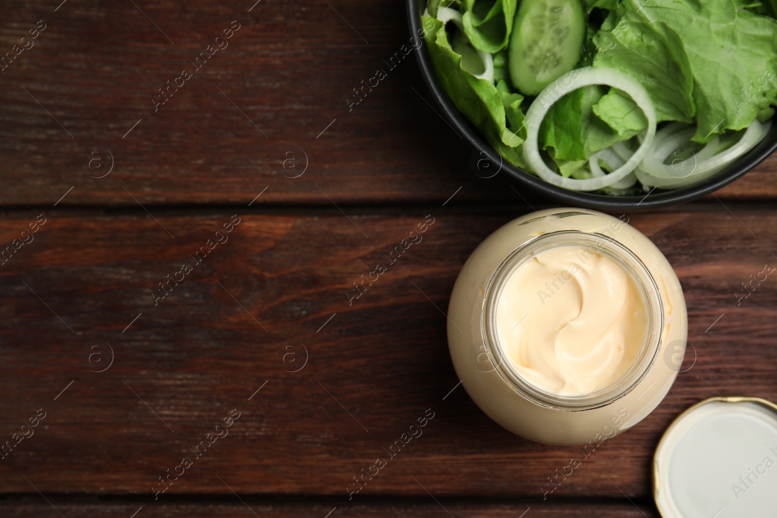 Photo of Jar of delicious mayonnaise and fresh salad on wooden table, flat lay. Space for text