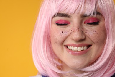Photo of Happy woman with bright makeup and glitter freckles on yellow background, closeup