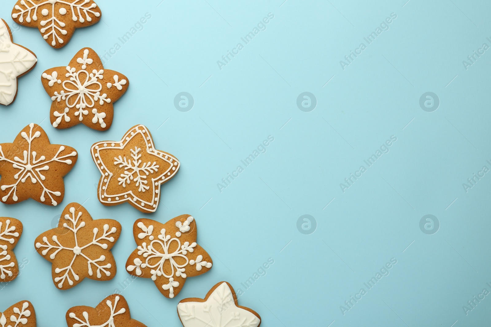 Photo of Tasty star shaped Christmas cookies with icing on light blue background, flat lay. Space for text