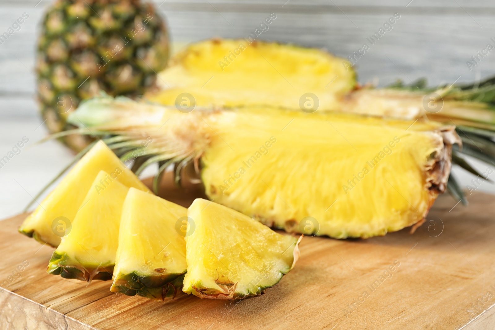 Photo of Cut fresh juicy pineapple on wooden board, closeup