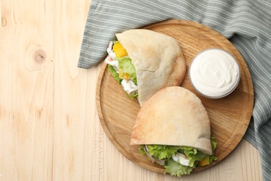 Photo of Delicious pita sandwiches with chicken breast and vegetables on wooden table, flat lay