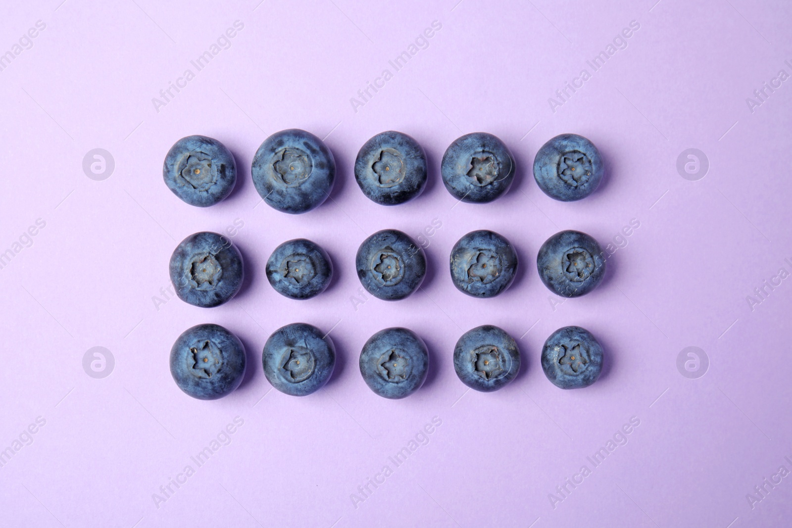 Photo of Tasty ripe blueberries on violet background, flat lay