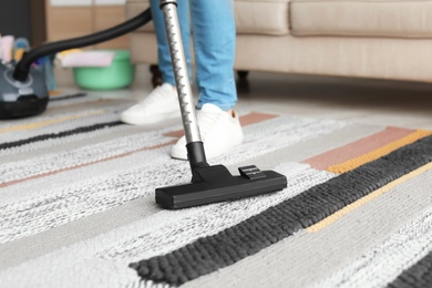 Man hoovering carpet with vacuum cleaner at home