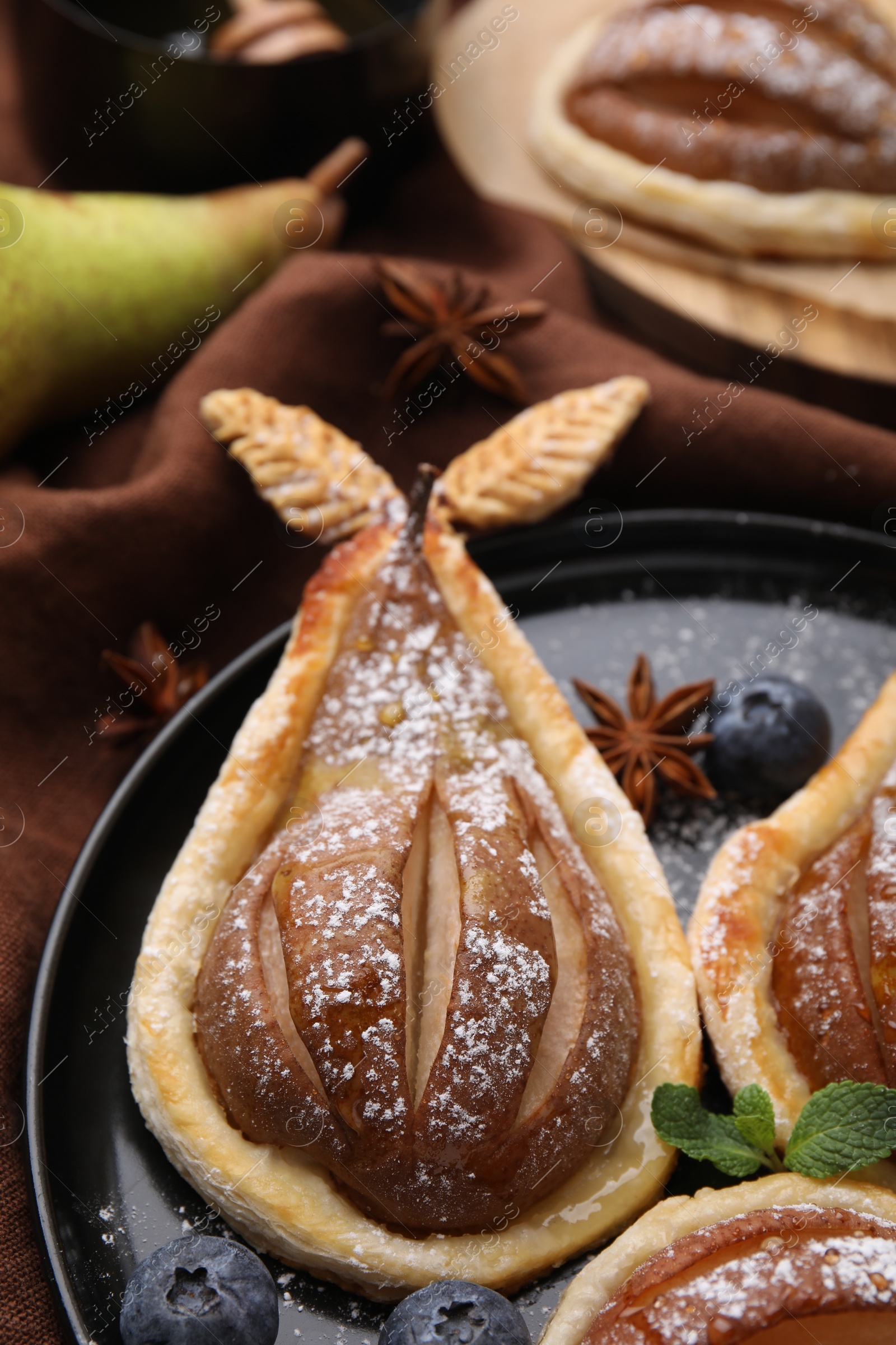 Photo of Delicious pears baked in puff pastry with powdered sugar served on table, closeup