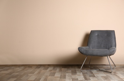 Photo of Stylish chair near color wall, space for text. Interior design