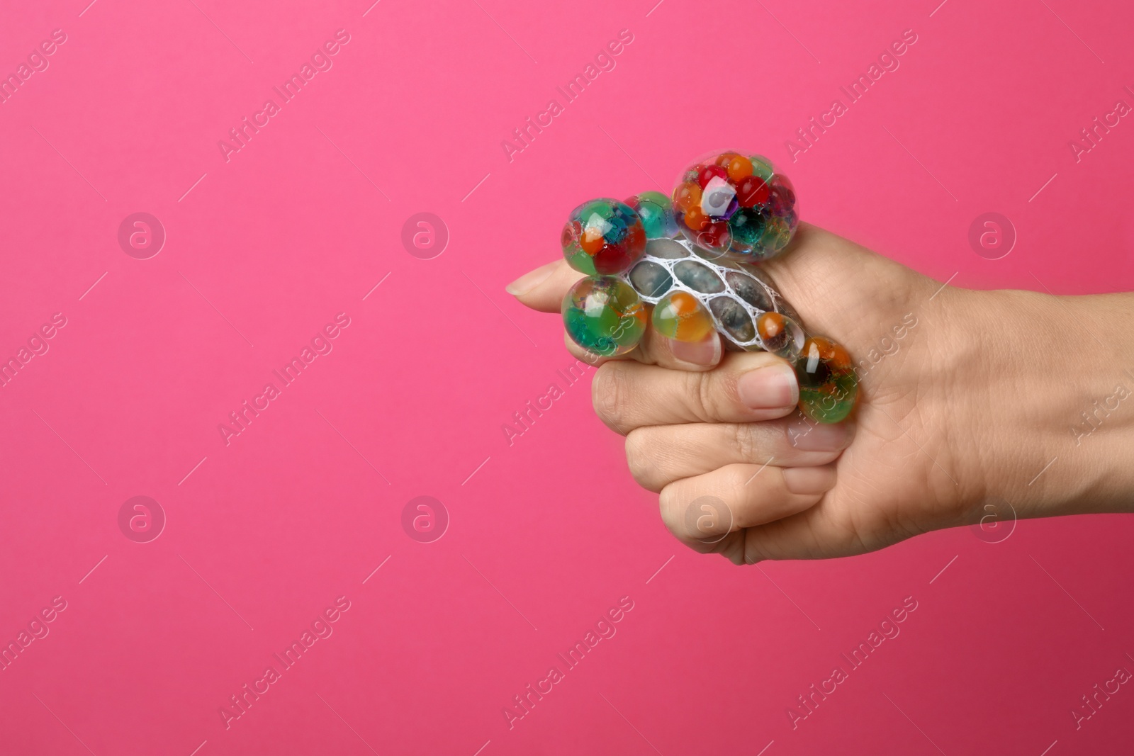 Photo of Woman squeezing colorful slime on pink background, closeup. Antistress toy