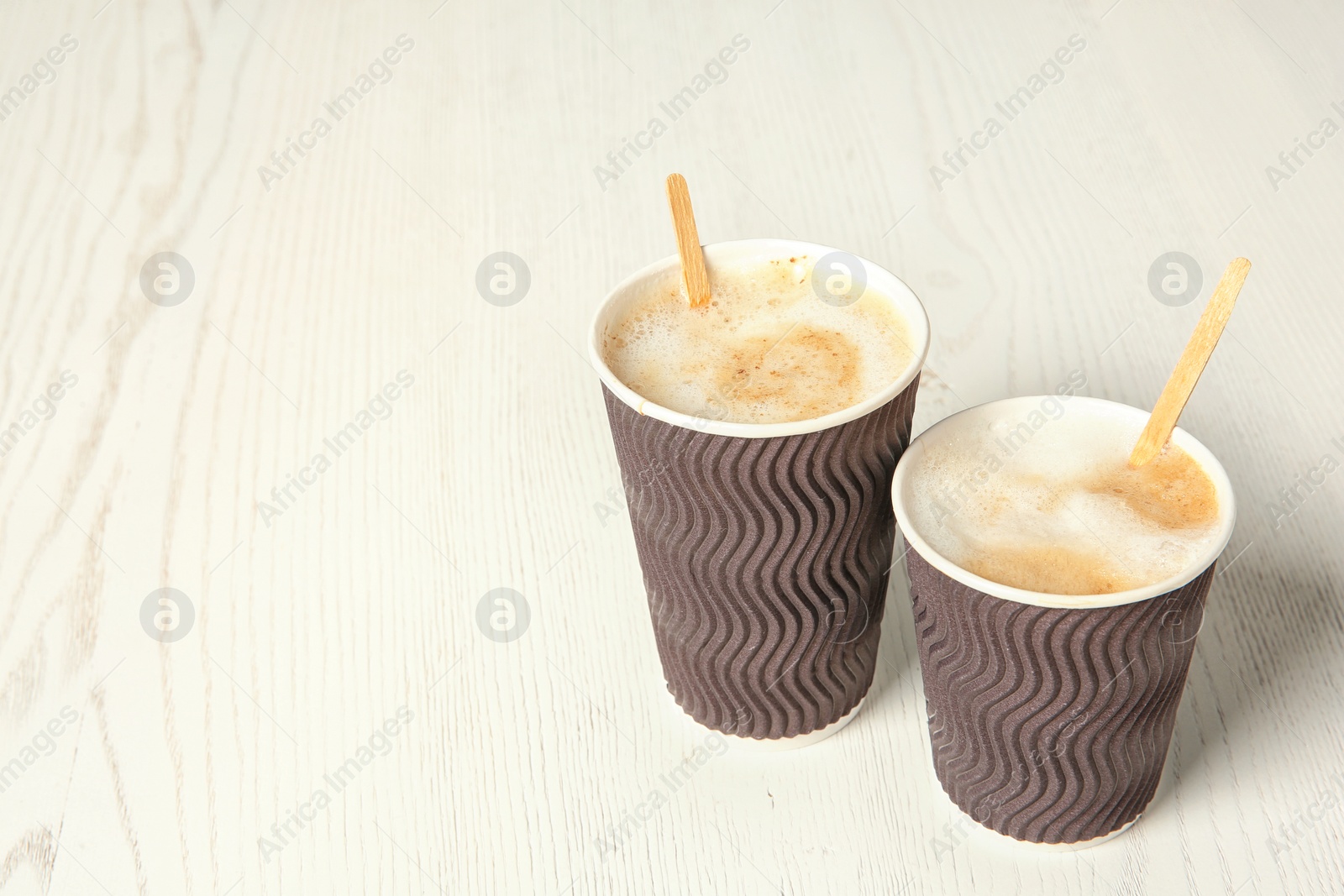 Photo of Cardboard cups of coffee on wooden background. Space for text