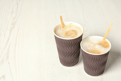 Cardboard cups of coffee on wooden background. Space for text