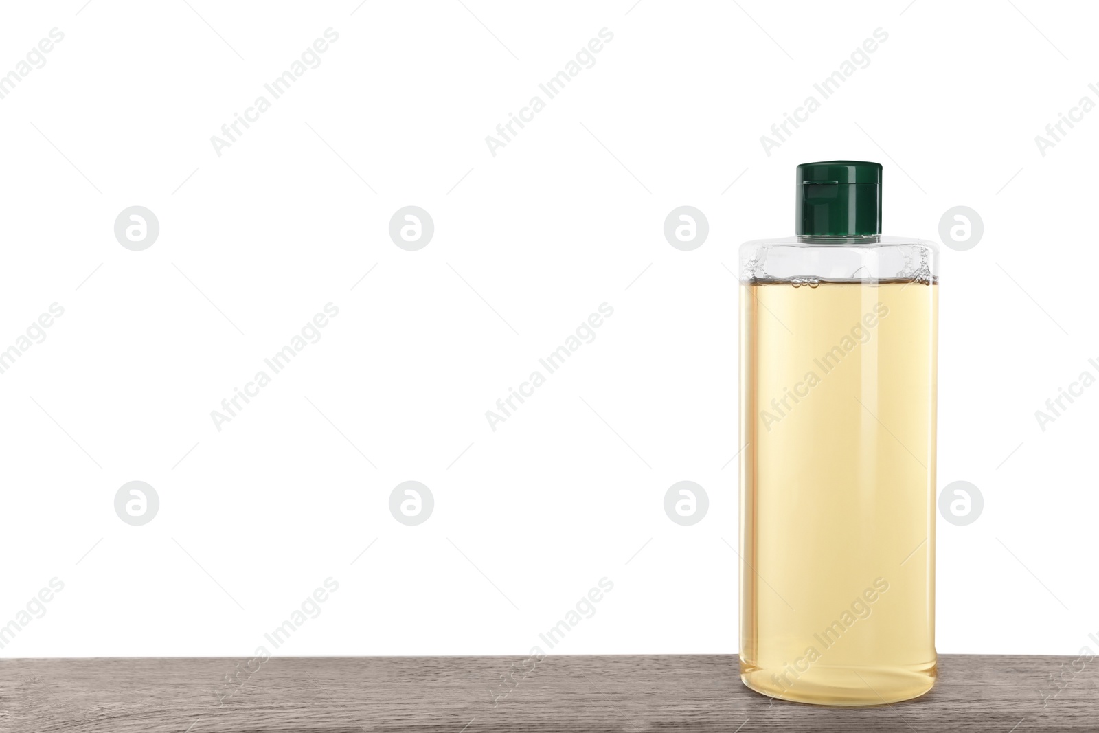 Photo of Micellar water in bottle on wooden table against white background. Space for text