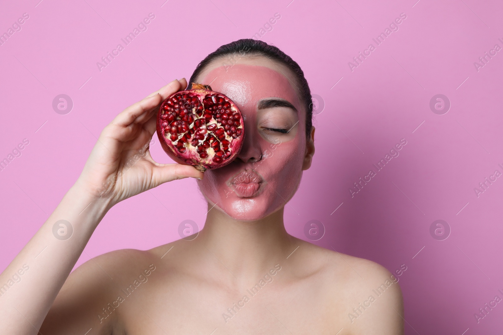 Photo of Woman with pomegranate face mask and fresh fruit on pink background