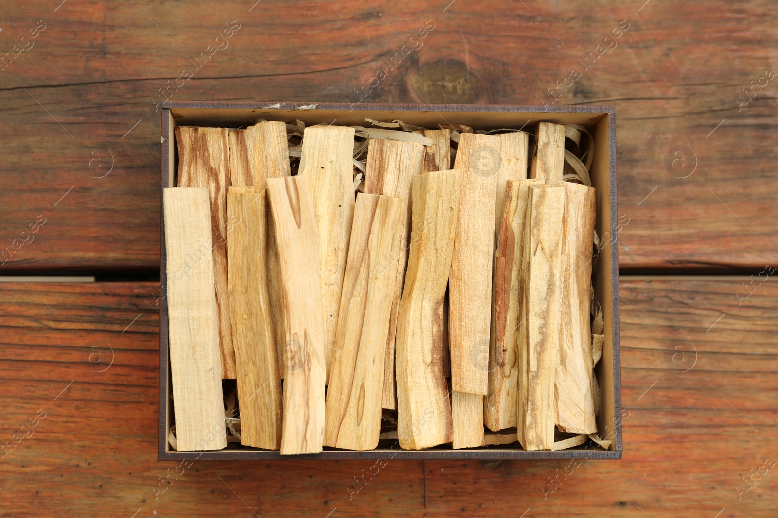 Photo of Palo Santo sticks in box on wooden table, top view