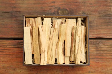 Photo of Palo Santo sticks in box on wooden table, top view