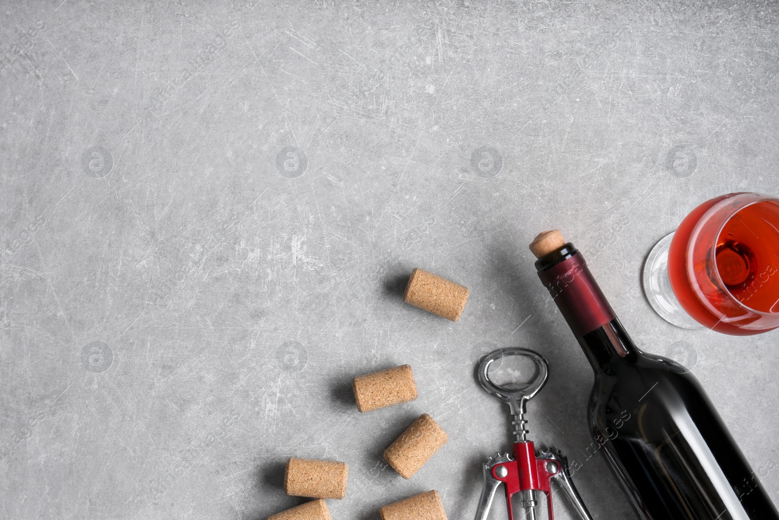 Photo of Wine corks, bottle, glass of drink and corkscrew on light grey table, flat lay. Space for text