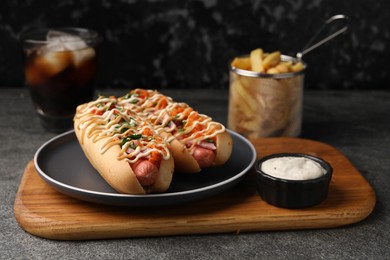 Delicious hot dogs with bacon, carrot and parsley served on grey table