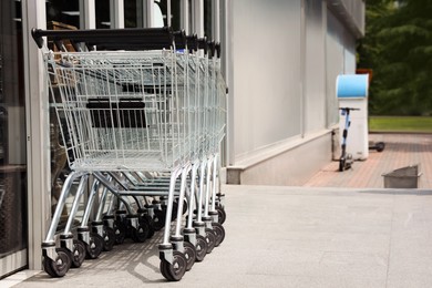 Photo of Row of shopping carts near store outdoors, space for text