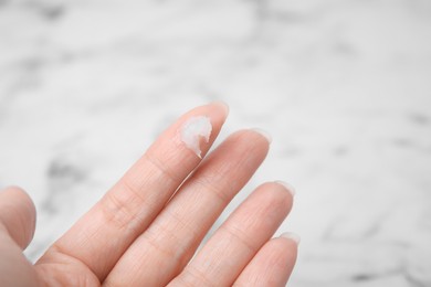 Photo of Woman applying petroleum jelly onto her finger against blurred background, closeup