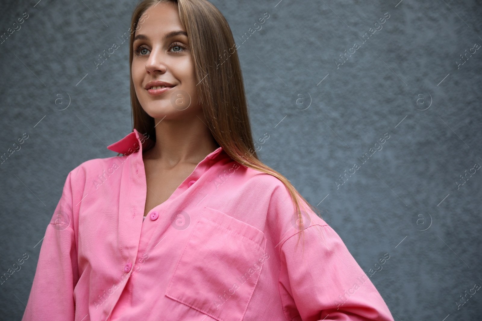 Photo of Beautiful young woman near grey wall, space for text