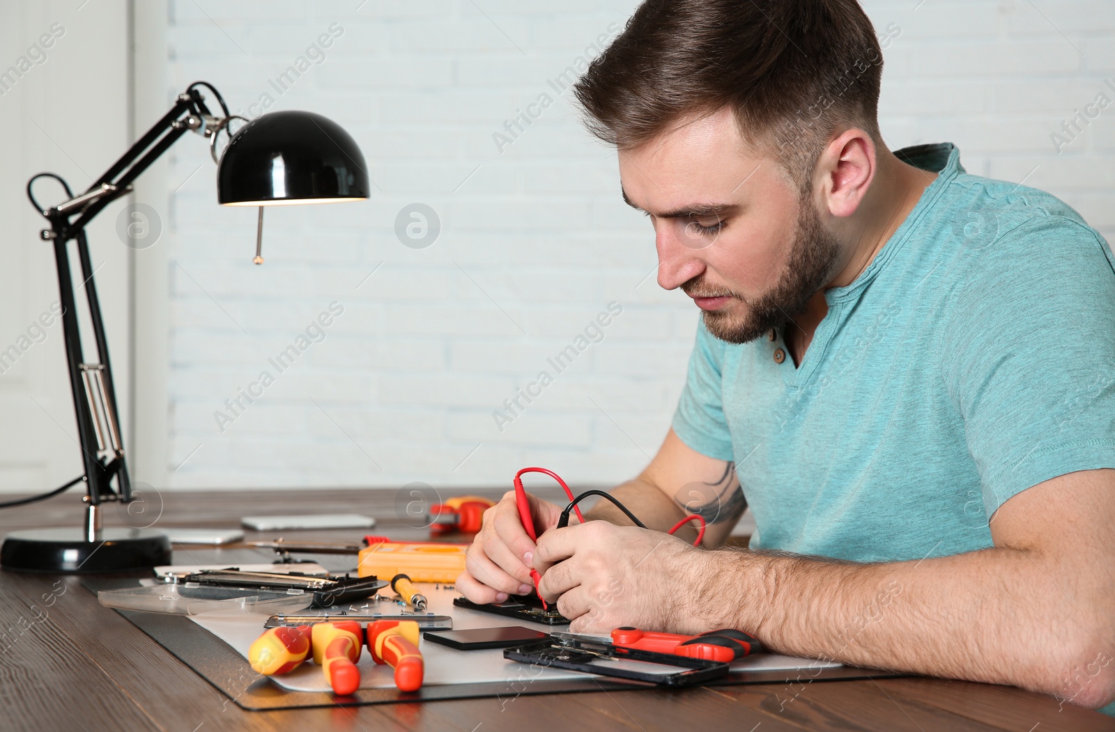 Photo of Technician checking mobile phone at table in repair shop