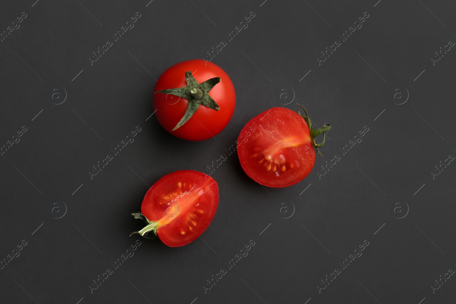 Photo of Whole and cut fresh cherry tomatoes on black background, flat lay